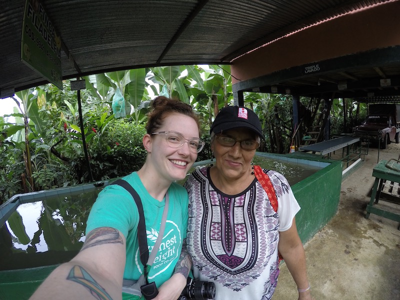 Kate in an Honest Weight tee posing with a woman in an Equal Exchange hat