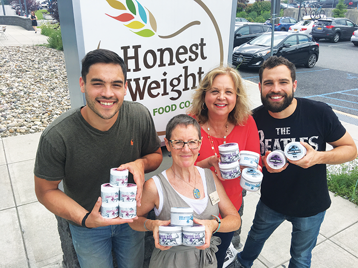 RAD's Sue, Zak and Max Kerber with Honest Weight's Jo-Ann Long in front of the HWFC sign holding RAD Jurassic World Products.