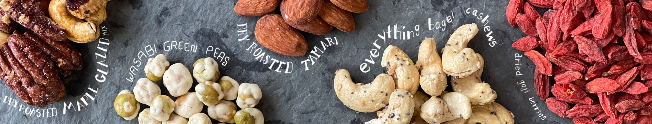 assorted bulk foods mounded on a slate board with handwritten names around each selection